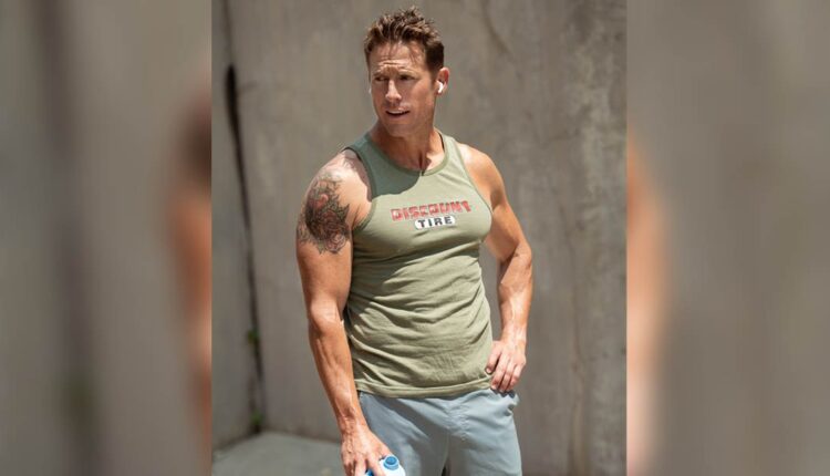 Andy McDermott wearing a muscle shirt and showing off his muscular arms at age 45